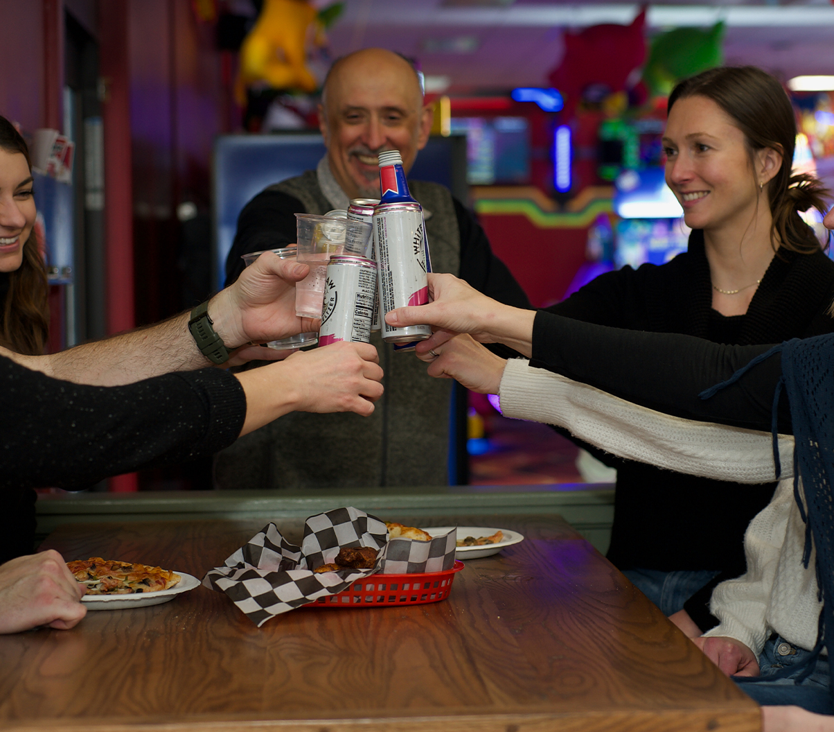 Adults enjoying alcoholic beverages at fun center arcade