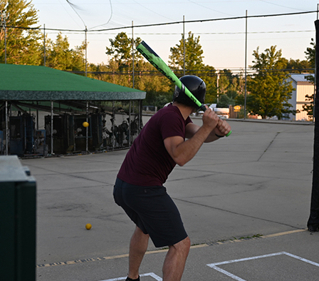 holding a bat in the batting cage