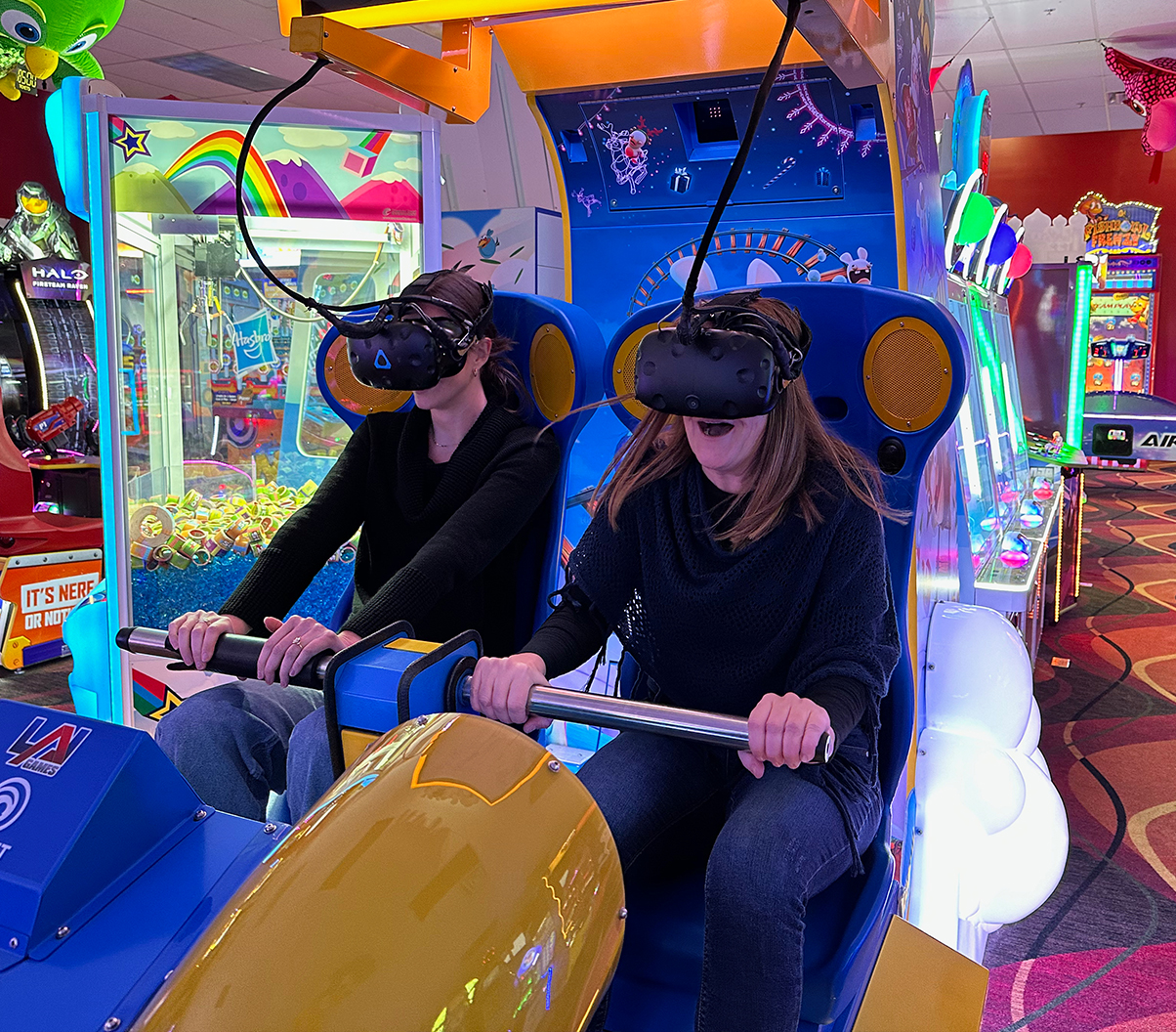 Two women playing arcade VR game.