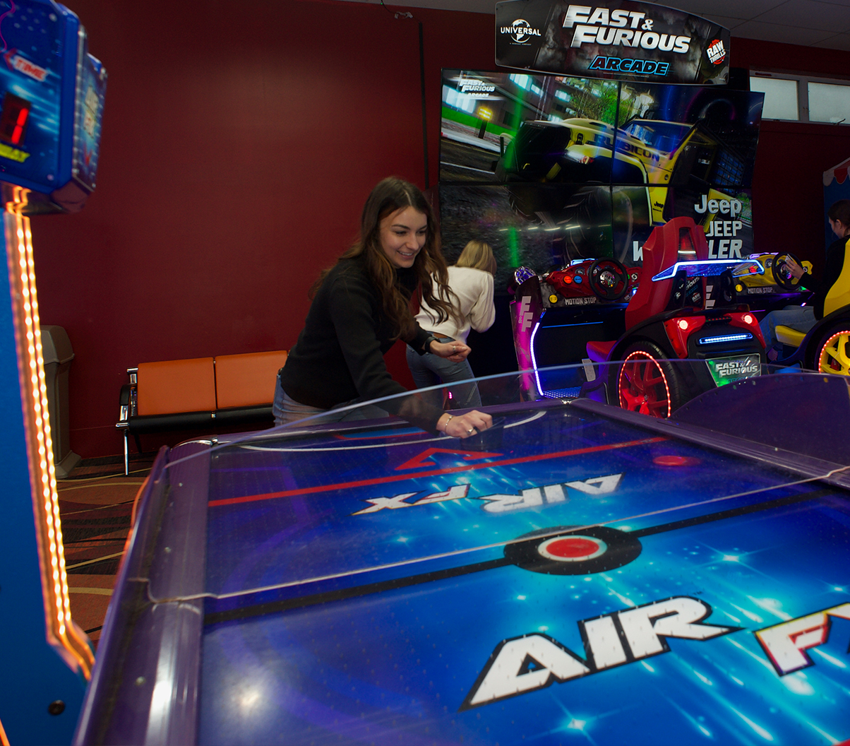 Women playing air hockey in an arcade.